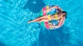 Aerial drone view of little girl in swimming pool from above, kid swims on inflatable ring donut , child has fun in blue water Royalty Free Stock Photo