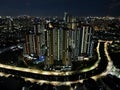 Aerial drone view of modern apartment building in Jakarta central business district at night with Jakarta cityscape. JAKARTA, Royalty Free Stock Photo