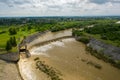 Aerial drone view. River water move down from with a water filled dam after heavy floods and rains.