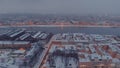 Aerial drone view of snow-covered roofs of buildings in a winter evening, night illumination of streets, night cityscap