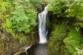 Aerial drone view of a tall waterfall in a narrow canyon surrounded by trees Sgwd Einion Gam, Wales, UK