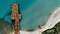 Aerial drone view to the beach with white sand, pier with sunchairs and sea. Luxury summer vacation and resort