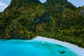 Aerial drone view of uninhabited tropical island with rugged mountains, rainforest jungle, sandy beach and tourist banca Royalty Free Stock Photo