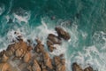 Aerial drone view of waves crashing on rocky coast. Scenic view of ocean waves breaking against shoreline. Generative AI