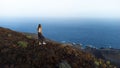 aerial drone view woman on the edge of a volcano crater looking at sea