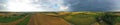 Aerial drone wide panoramic view on agricultural landscape with wheat field, village, meadows, forest and rain storm on horizon