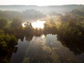 Aerial early morning view of trees and river. Beautiful foggy forest scene in autumn with orange and yellow foliage Royalty Free Stock Photo