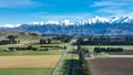 Aerial farming grazing and crop fields in rural countryside with a backdrop of the snow capped Mountain range under clear skies