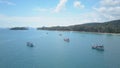 AERIAL: Fishing boats wait near sandy beach on a calm morning in stunning Krabi.