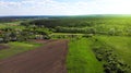 Aerial. Flight over the agricultural fields. Farmers houses and forest in the background.