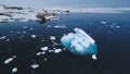 Aerial flight over Antarctic iceberg amid ocean.