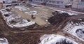 Aerial flight over the development of a site of new structures, where heavy machinery and construction workers work with Royalty Free Stock Photo
