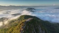 Aerial fly orbiting around mountain peak revealing sunrise over the sea of mist