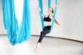 Aerial fly yoga in white gym. Young beautiful women practicing stretching pilates in blue hammock