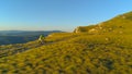 AERIAL: Flying above an active man riding his bicycle down the grassy mountain.