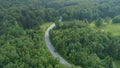 AERIAL: Flying above cars driving down road winding through dark green forest. Royalty Free Stock Photo