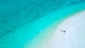 AERIAL: Flying above female tourist suntanning on the empty tropical beach. Royalty Free Stock Photo