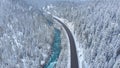 AERIAL: Flying above the picturesque winter forest and emerald colored stream. Royalty Free Stock Photo