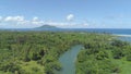 AERIAL: Flying along tropical river estuary on a sunny day on remote island.