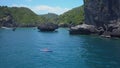 AERIAL: Flying along woman and tourists kayaking near towering limestone cliffs. Royalty Free Stock Photo