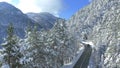 AERIAL: Flying behind dark tourist car driving through the snowy spruce forest. Royalty Free Stock Photo