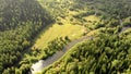 Aerial flying of drone over mountain river, field and forest. Beautiful top view of trees and hills.