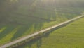 AERIAL: Flying high above unrecognizable person riding a bike along empty road. Royalty Free Stock Photo