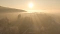 AERIAL: Flying over the endless forests covered in mist at scenic golden sunset.