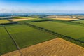 Aerial Flying over fields with straw bales at harvesting time, sunflowers and maize or corn, sunset time, top view. Far village Royalty Free Stock Photo