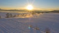 AERIAL: Flying over the large snow covered field on a sunny winter evening. Royalty Free Stock Photo