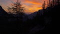 AERIAL Flying past spruce trees covering the rugged mountains at colorful sunset Royalty Free Stock Photo