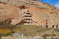 AERIAL: Flying towards an ancient Buddhist temple carved into a stone cliff.