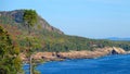 AERIAL: Flying towards the empty rocky coast filled with trees changing colors. Royalty Free Stock Photo