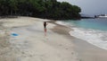 Aerial footage. Aerial view of Beautiful girl on sandy beach walking along the coast among the waves.