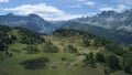 Aerial forward over blue alpine lake revealing mountain forest valley in sunny summer with clouds.Europe Alps outdoors