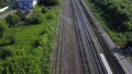 Aerial of four rows of long railways layng along green line of bushes and trees