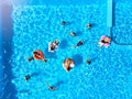 Aerial of friends having party in swimming pool with inflatable flamingo, swan, mattress. Happy young people relax at Royalty Free Stock Photo