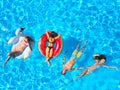 Aerial of friends having party in swimming pool with inflatable flamingo, swan, mattress. Happy young people relax at Royalty Free Stock Photo