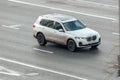 Aerial front side view rolling shot with BMW X7 car in motion. white crossover driving fast along the street in city Royalty Free Stock Photo