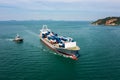 Aerial in front view container ship and tugboat dragging floating in green sea, business and industry Transportation cargo Royalty Free Stock Photo