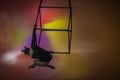 Aerial gymnast in black leotard on multicolored background of studio. Female acrobat performing on a cube, performing