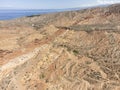 Aerial high angle view of the eroded landscape of Skazka Canyon in Kyrgyzstan with Lake Issyk-Kul in background