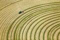 An aerial image of a farmer cutting and wind rowing alfalfa hay.