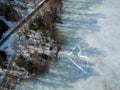 Aerial image of frozen lake with white heart shape on ice, trees on bank and way, drone image