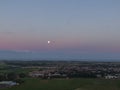 Aerial image of purple sky after sunset with full moon over flat meadow land, sea and village on dutch island Texel