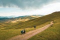 Aerial inspirational view excited joyful caucasian male cyclist standing by red touring bicycle looking to scenic mountains