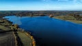 Aerial view 4k wide angle of fields and Rutland water, England, cloudy skies and green patches of forest. Royalty Free Stock Photo