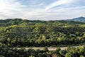 Aerial landscape of 4 lane road with residential area, forest, mountain, blue sky and sunlight with high angle view of main road