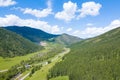 Landscape with mountains, green trees, field, road and river under blue sky and clouds in summer Royalty Free Stock Photo