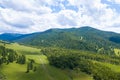 Landscape with mountains, green trees, field, road and river under blue sky and clouds in summer Royalty Free Stock Photo